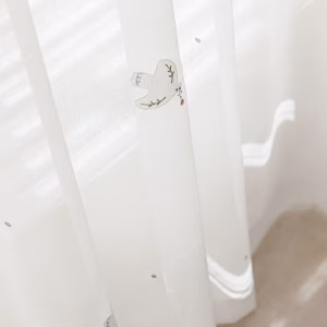 Close-up van een geborduurd wit duifje op een transparante kinderkamer vitrage