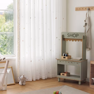 Vitrage met maantjes en sterretjes in een sfeervolle kinderkamer.