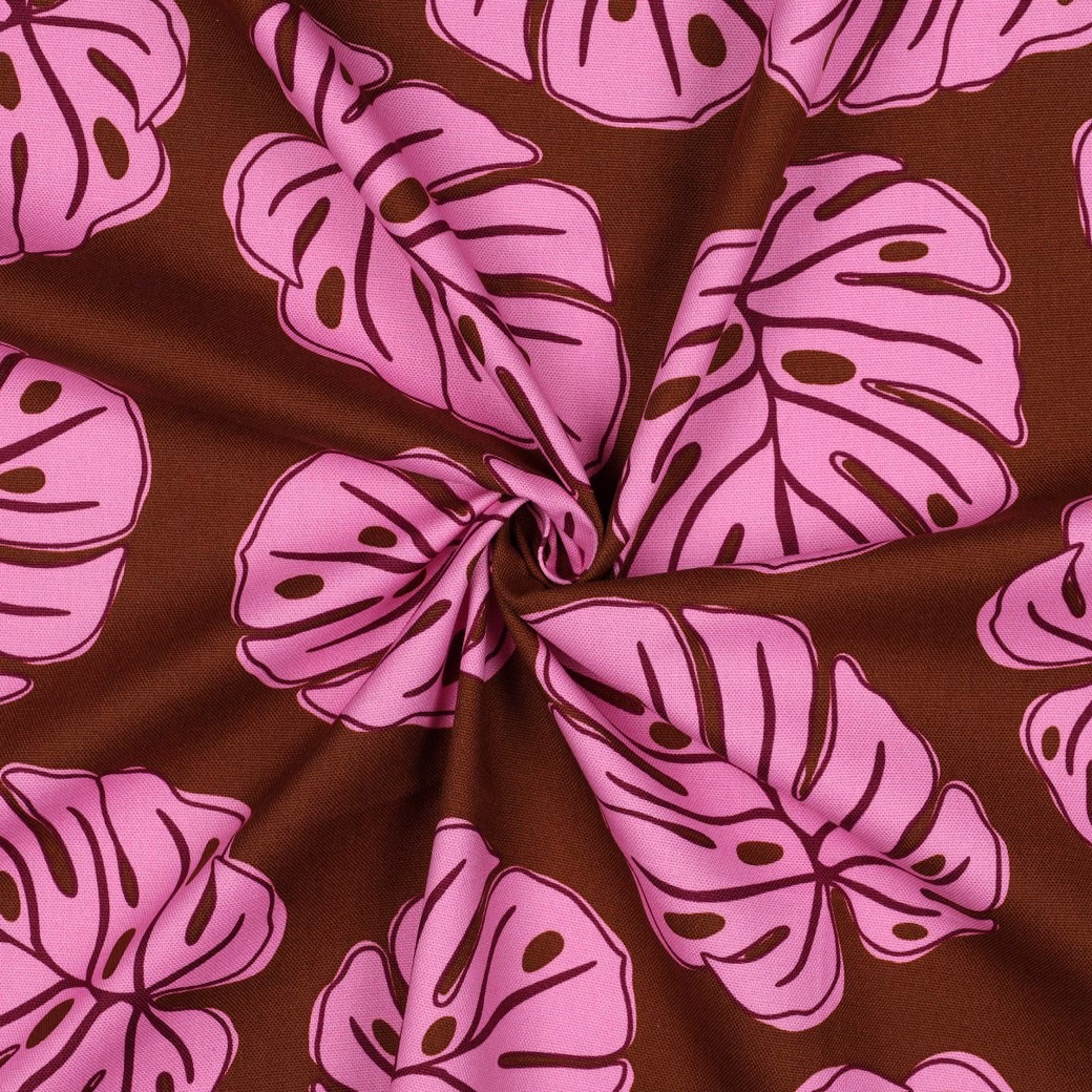 Bruine katoenen gordijnstof met roze tropische bladeren, in een spiraal gedrapeerd.