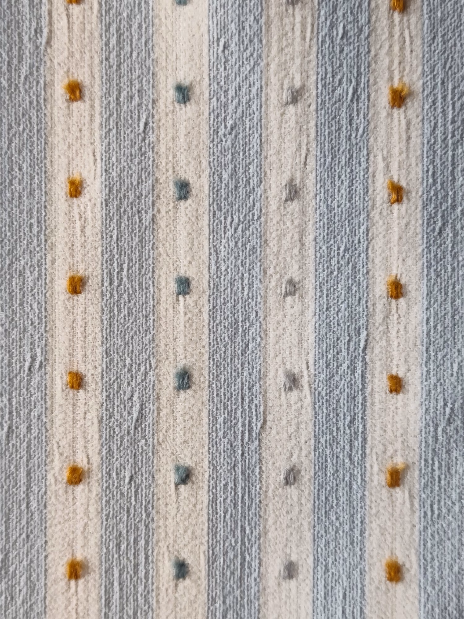 Detail van een stofstaal met blauwe en lichte strepen en kleine gekleurde vierkantjes