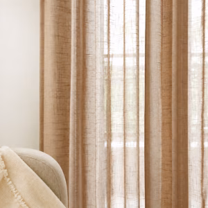 Beige lichtdoorlatende gordijnen met fijne weefstructuur in een licht interieur.