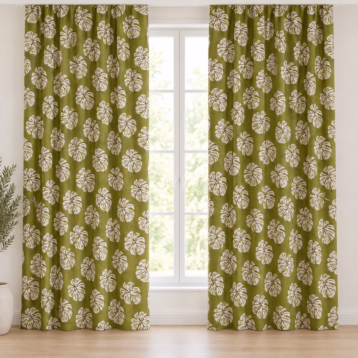 Groene gordijnen met crèmekleurige tropische bladeren, hangend voor een raam.
